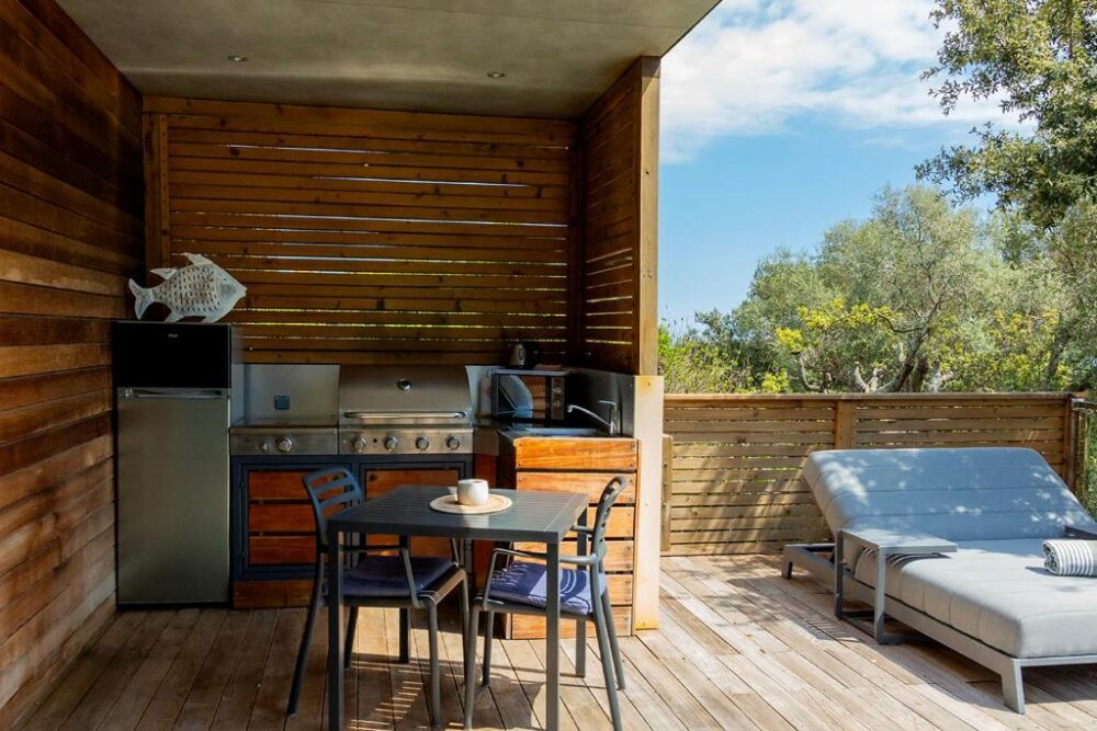 Cuisine extérieure avec mobilier sur terrasse en bois.