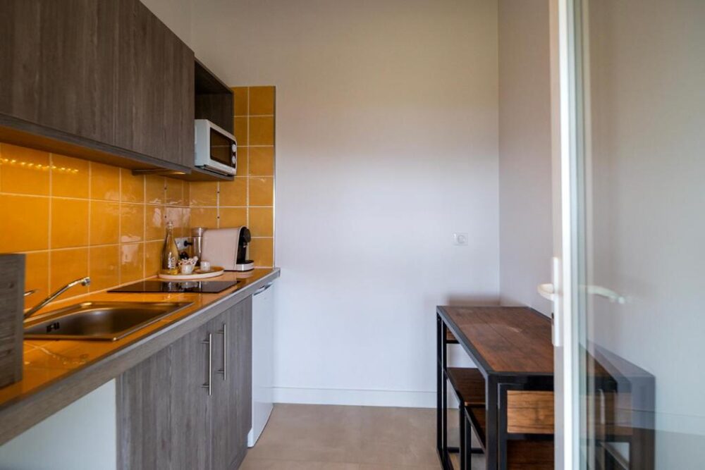 Cuisine moderne avec carrelage orange et meubles en bois.