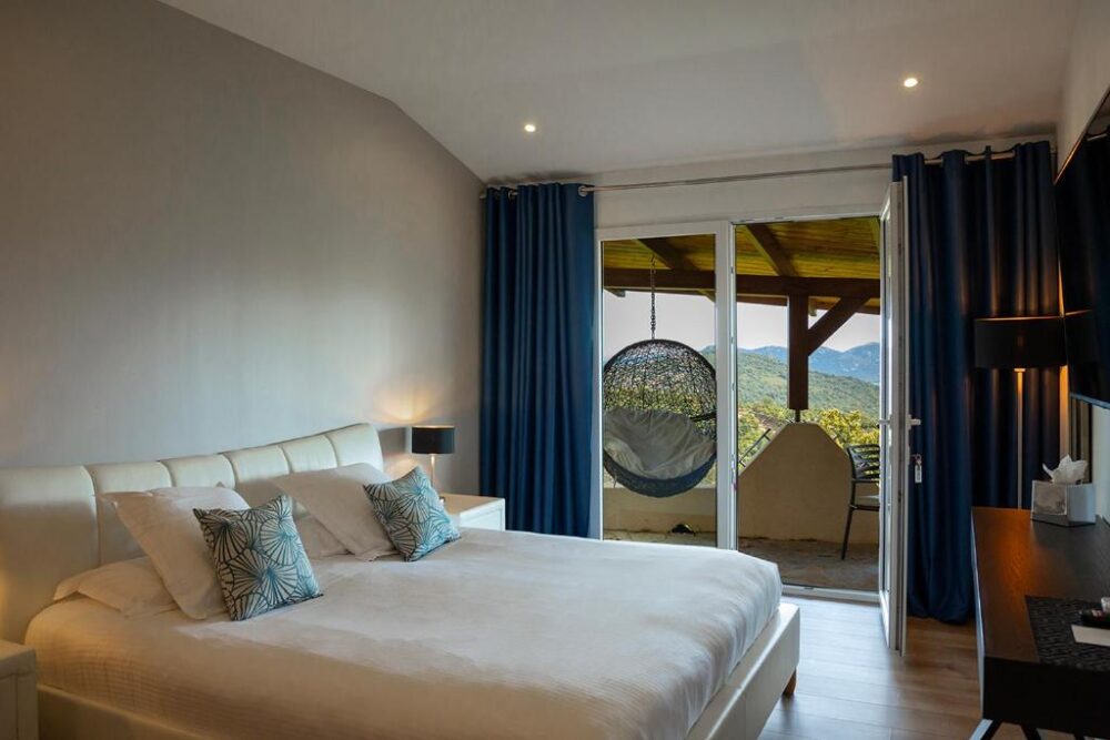 Chambre avec lit, vue balcon et montagnes.