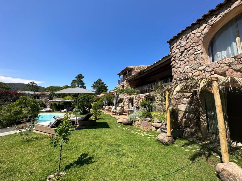Villa en pierre avec piscine et jardin verdoyant.