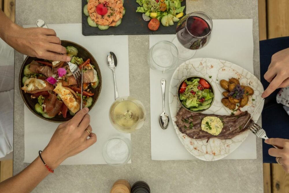 Deux personnes dégustent des plats raffinés et du vin.