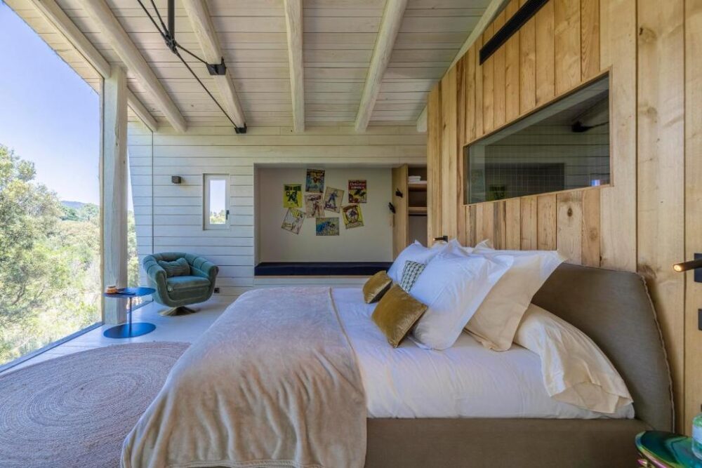 Chambre moderne avec lit et fauteuil verts.