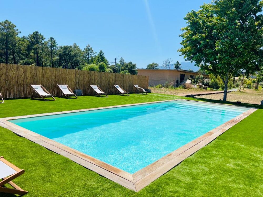 Piscine extérieure entourée de transats sur pelouse.