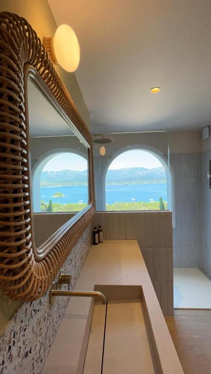 Salle de bain avec vue sur mer et miroir.
