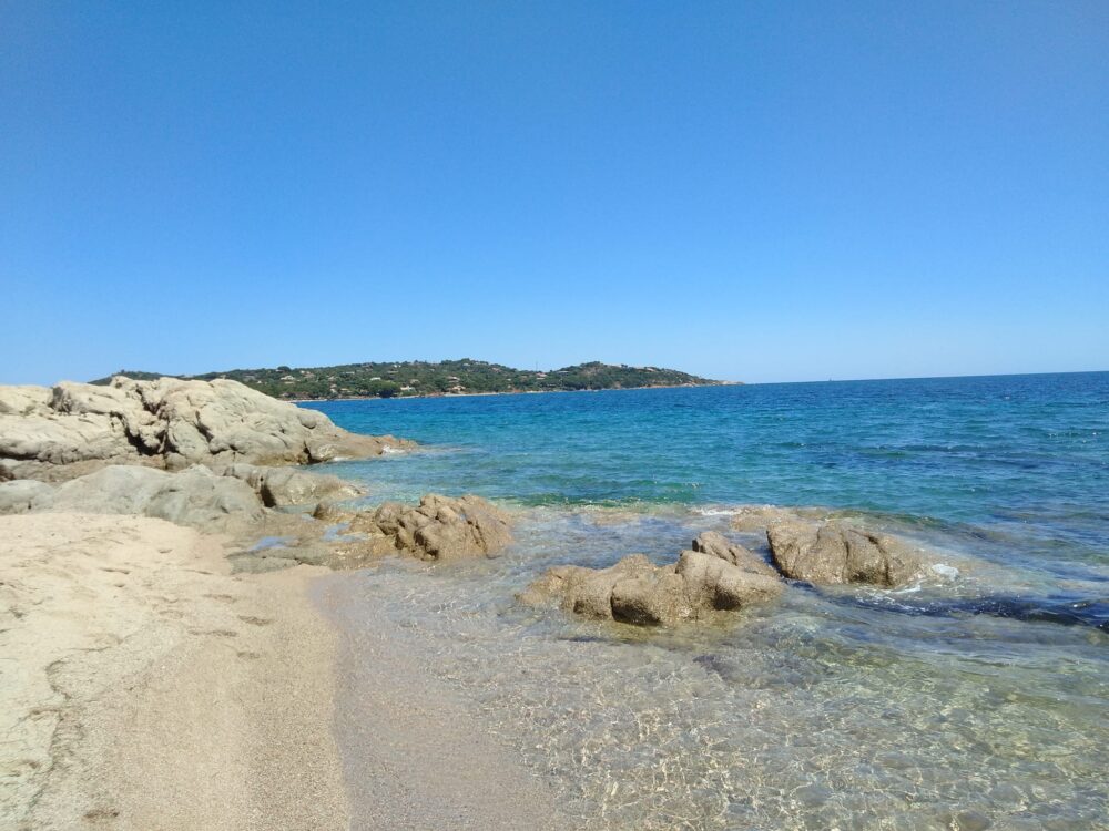 Plage avec rochers, mer bleue et ciel clair.
