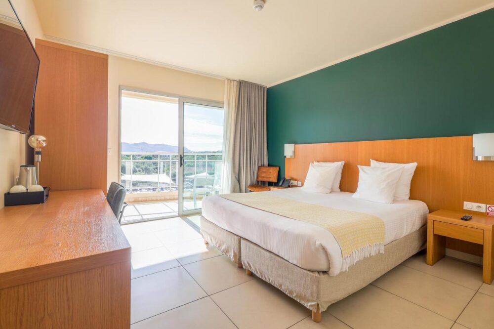 Chambre d'hôtel moderne avec balcon et vue.
