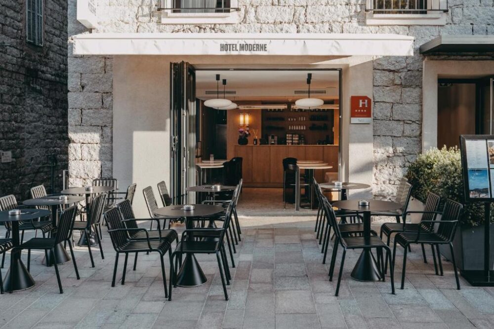 Terrasse de café moderne avec tables et chaises noires.