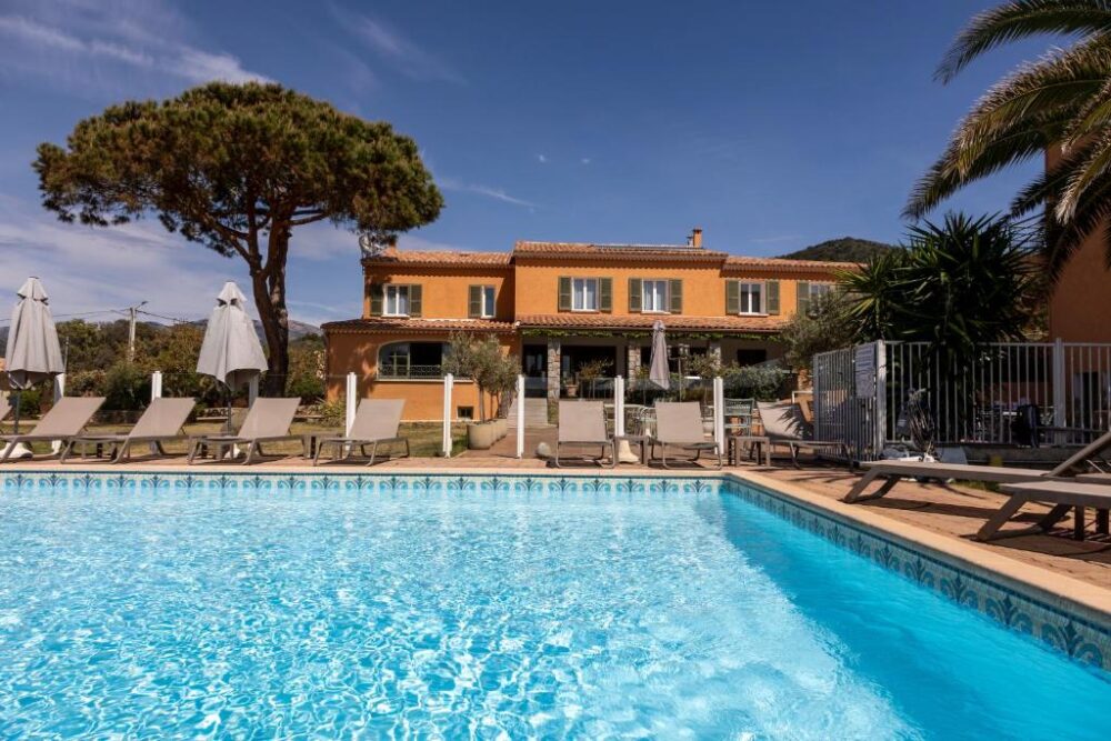 Piscine devant maison méditerranéenne ensoleillée.