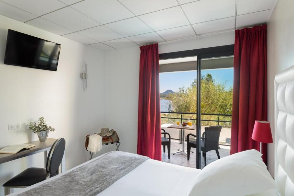 Chambre d'hôtel avec balcon vue sur lac.