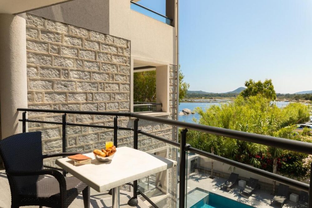 Balcon ensoleillé avec vue sur la piscine et lac.
