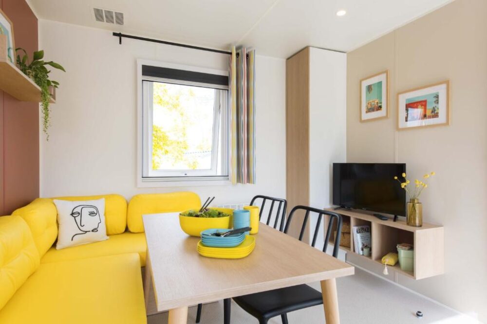 Salon moderne avec canapé jaune et table à manger.