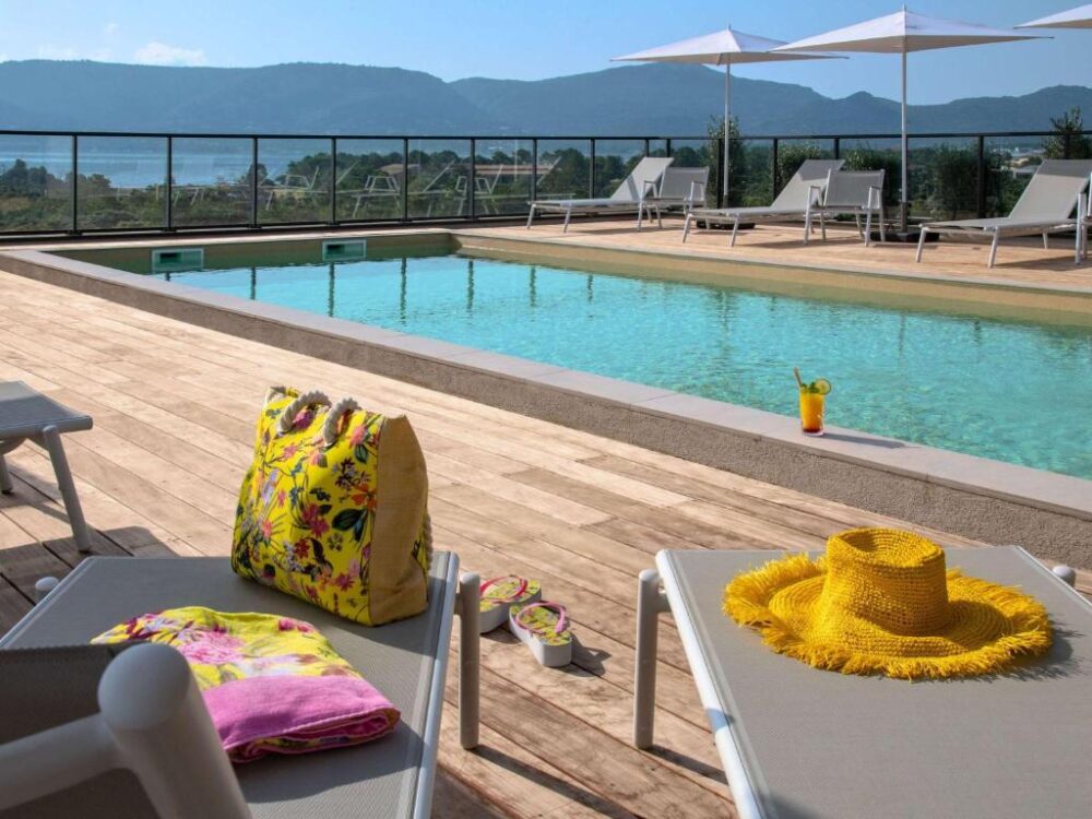 Piscine extérieure ensoleillée avec chaises longues.