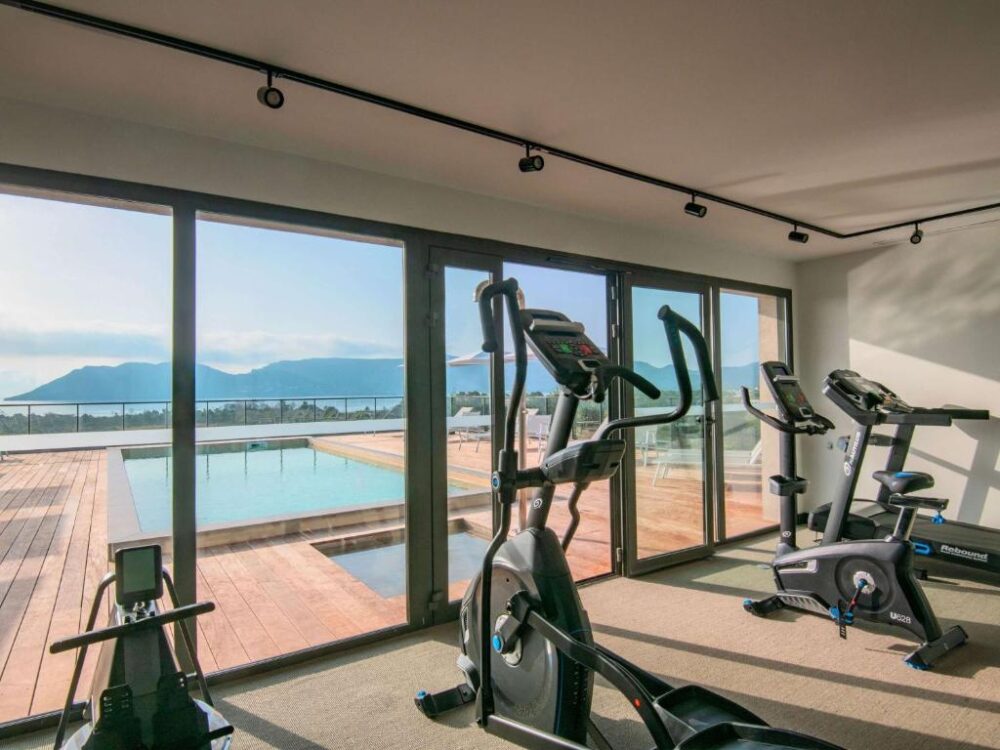 Salle de sport avec vue sur piscine panoramique.