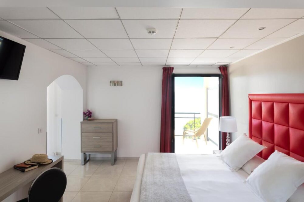 Chambre d'hôtel lumineuse avec vue sur balcon.