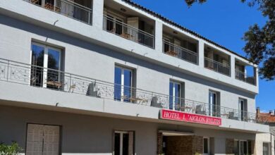 Façade de l'hôtel avec balcon et enseigne rouge.