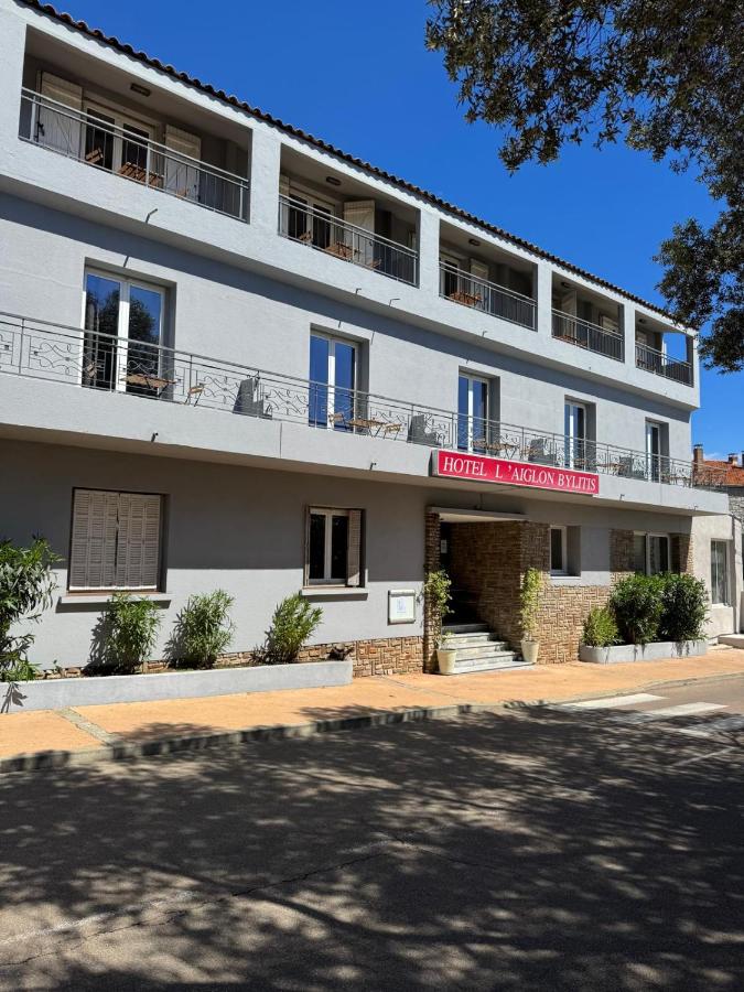 Façade de l'hôtel avec balcon et enseigne rouge.