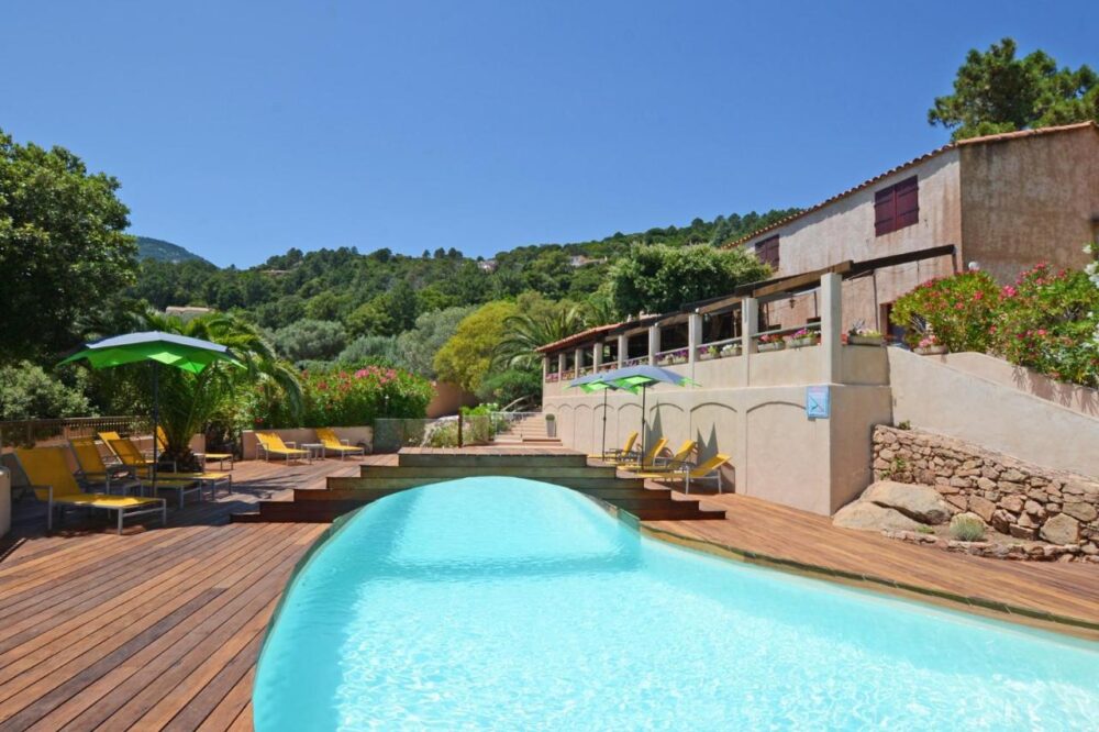 Piscine extérieure avec transats et parasols verts.