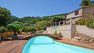 Piscine extérieure avec transats et parasols verts.