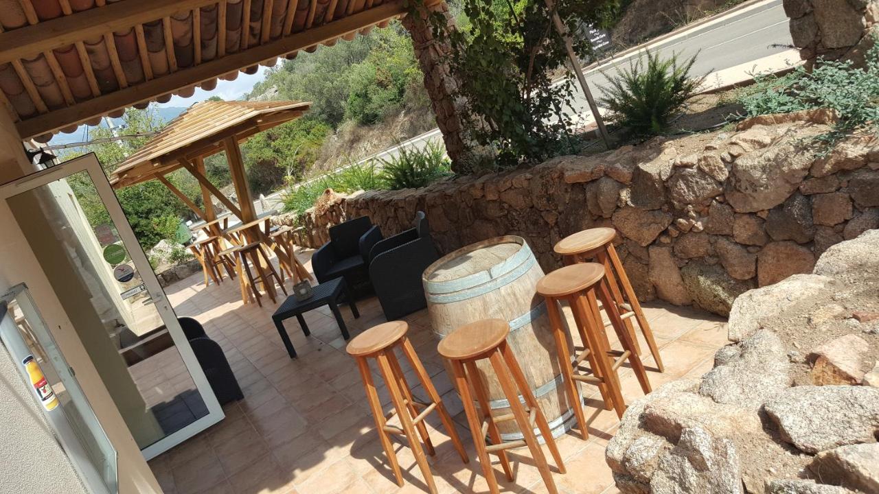 Terrasse ensoleillée avec barils et tabourets.