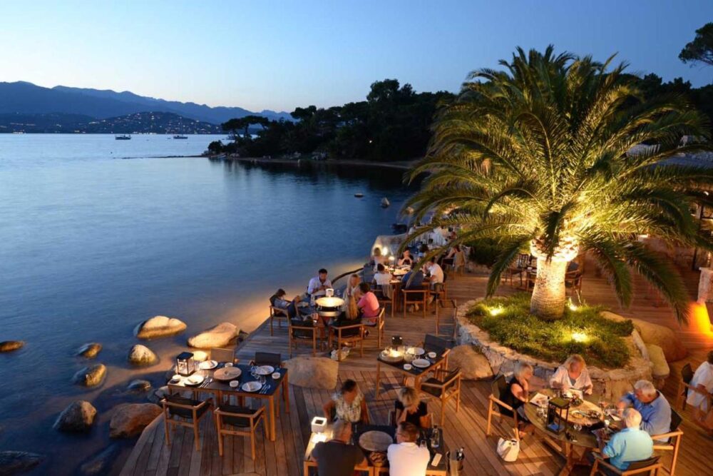 Terrasse de restaurant au bord de l'eau, soirée.