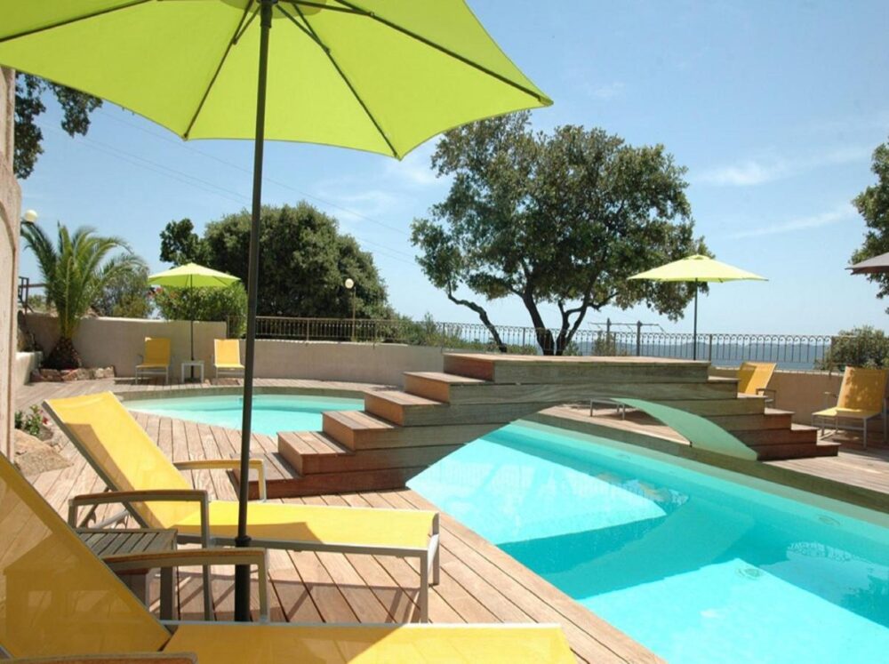 Piscine avec parasols et chaises longues jaunes.