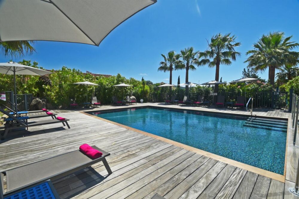 Piscine extérieure avec chaises longues et parasols.