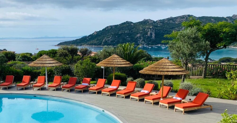 Piscine avec transats et vue sur la mer.
