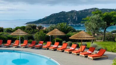 Piscine avec transats et vue sur la mer.