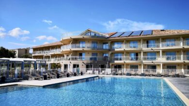 Hôtel moderne avec piscine et chaises longues ensoleillées.
