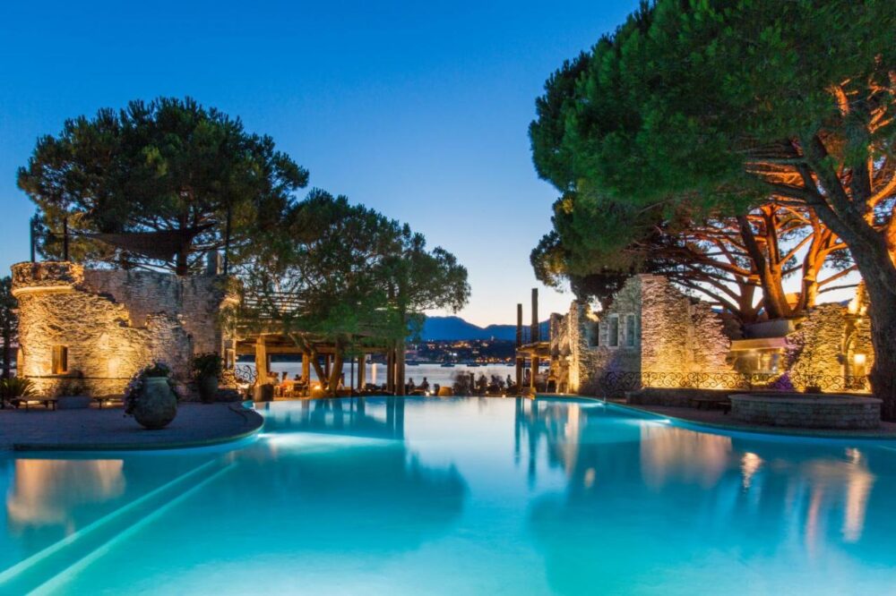 Piscine éclairée au crépuscule, arbres et montagnes.