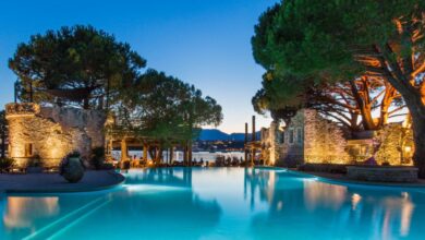 Piscine éclairée au crépuscule, arbres et montagnes.