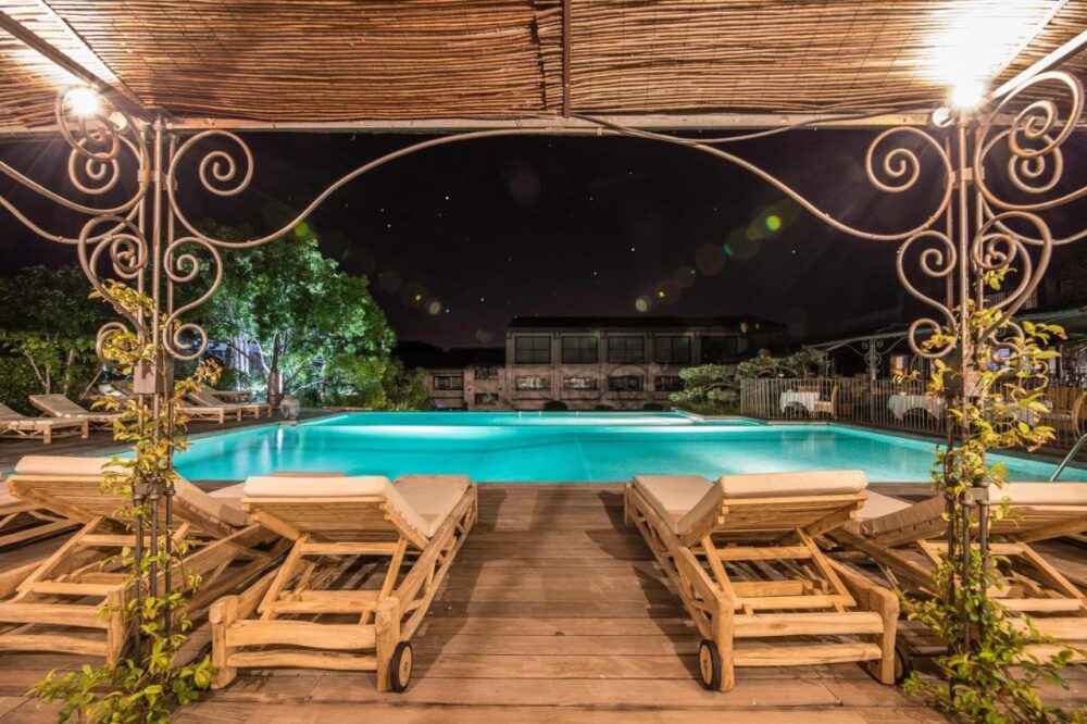 Piscine extérieure éclairée la nuit avec transats.