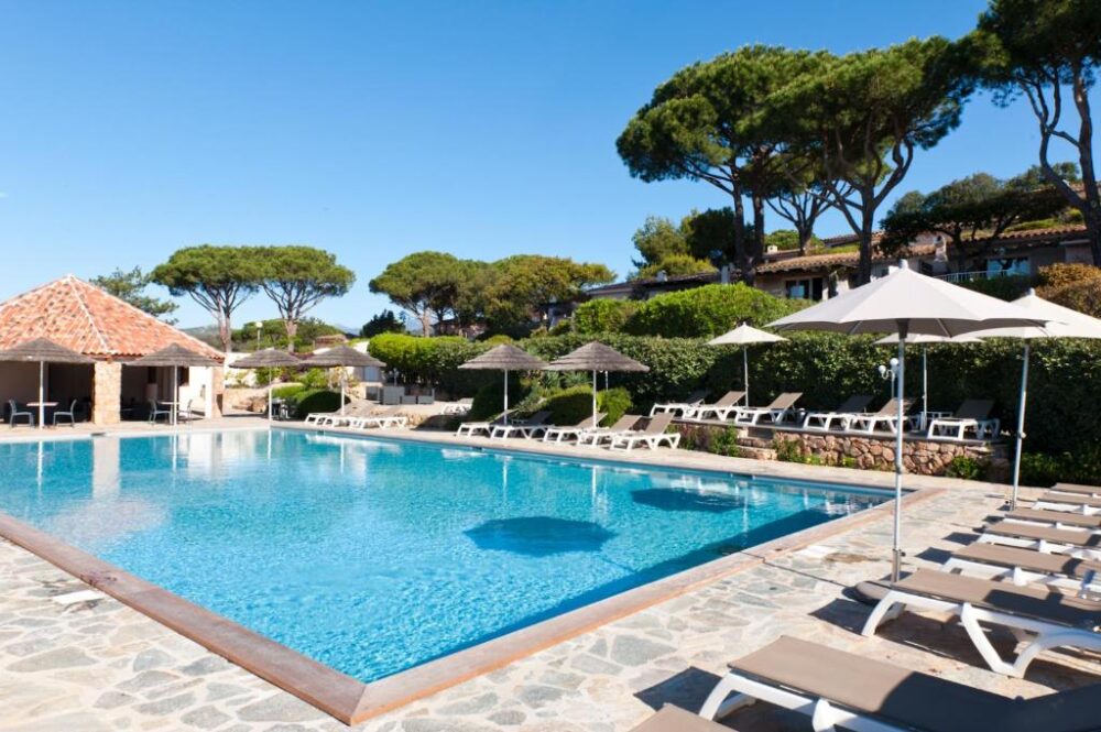 Piscine extérieure entourée de chaises longues et parasols.