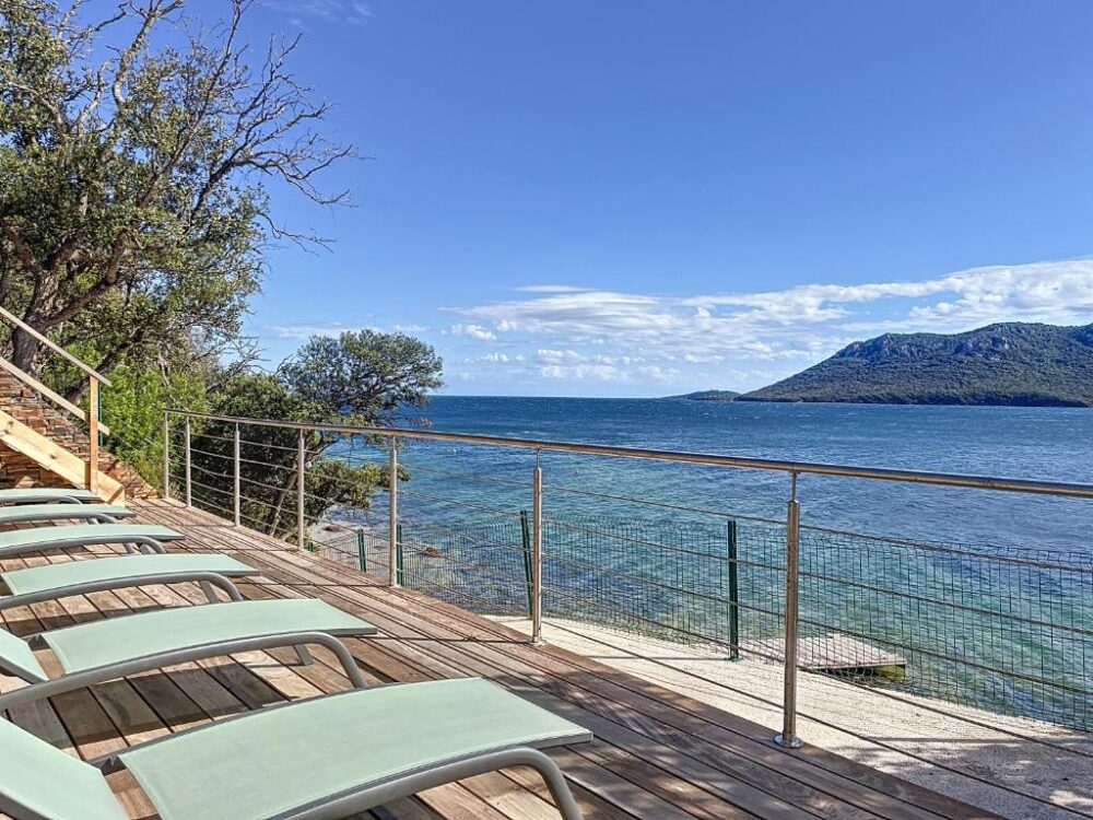 Terrasse en bois surplombant la mer, chaises longues