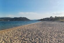 Plage sableuse avec mer et montagnes.