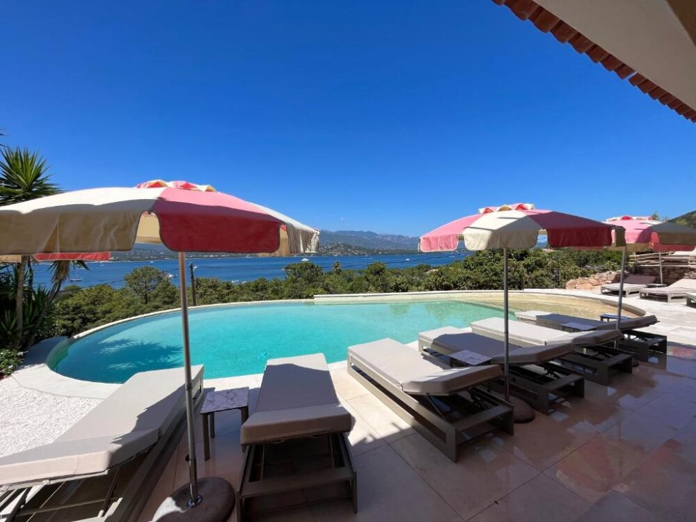 Piscine avec vue sur la mer et parasols colorés.