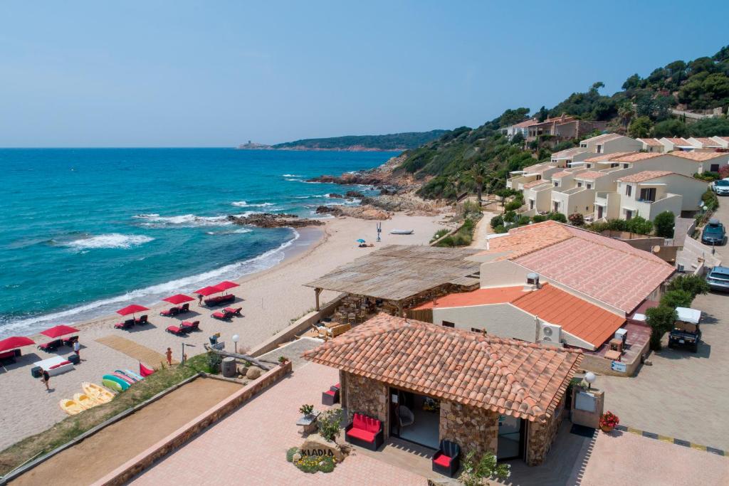 Plage méditerranéenne avec parasols rouges et villas.