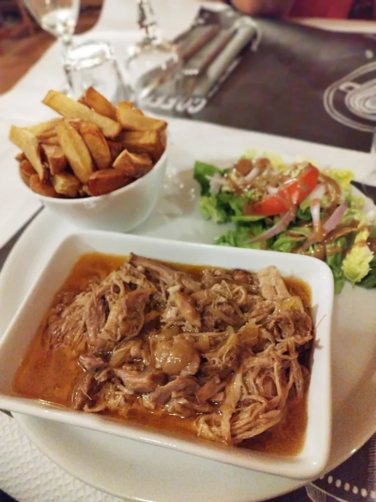 Assiette de viande, frites et salade.