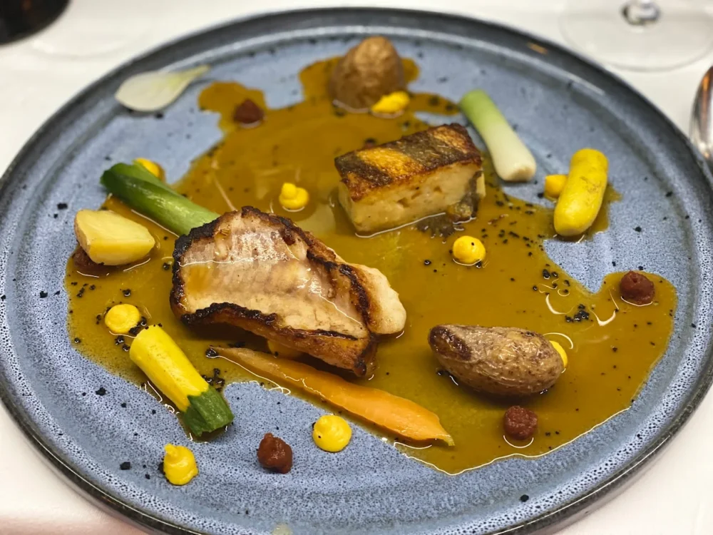 Assiette gastronomique avec poisson et légumes colorés.