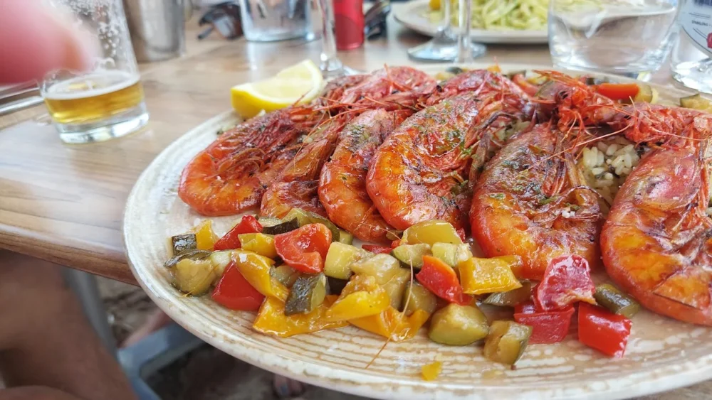 Assiette crevettes grillées et légumes colorés.