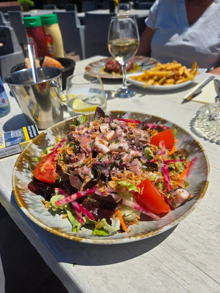 Salade colorée avec verre de vin en terrasse.
