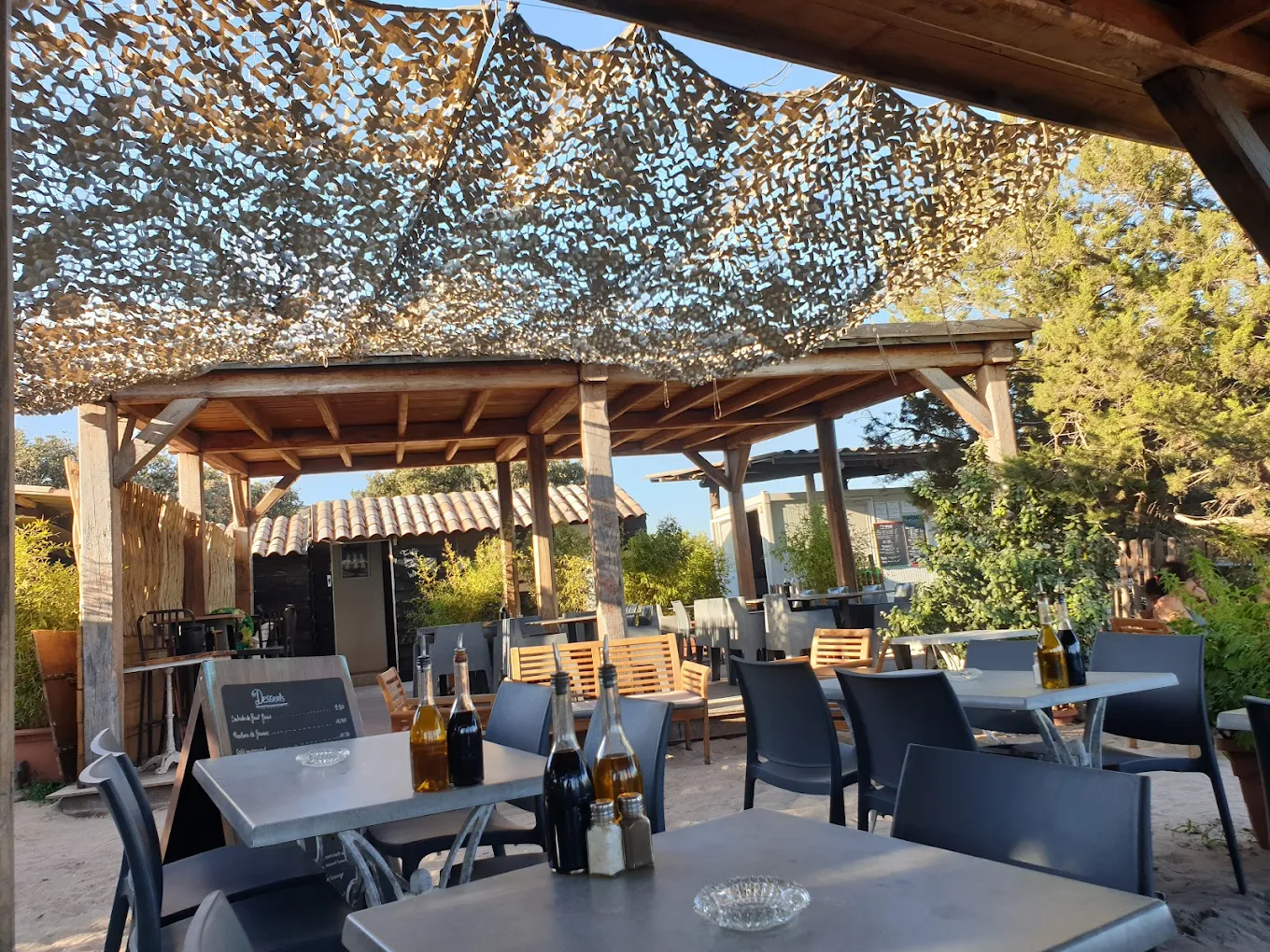 Terrasse extérieure avec tables et chaises sous abri.