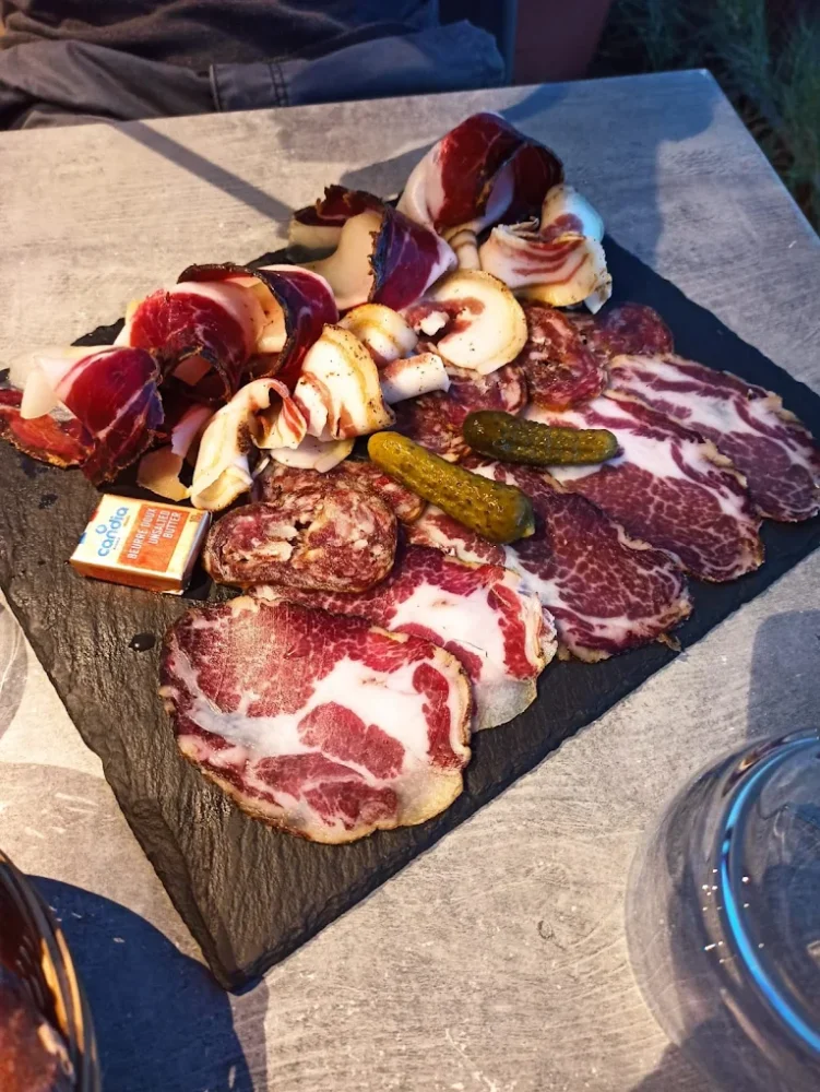 Plateau de charcuterie avec cornichons, fromage sur table.