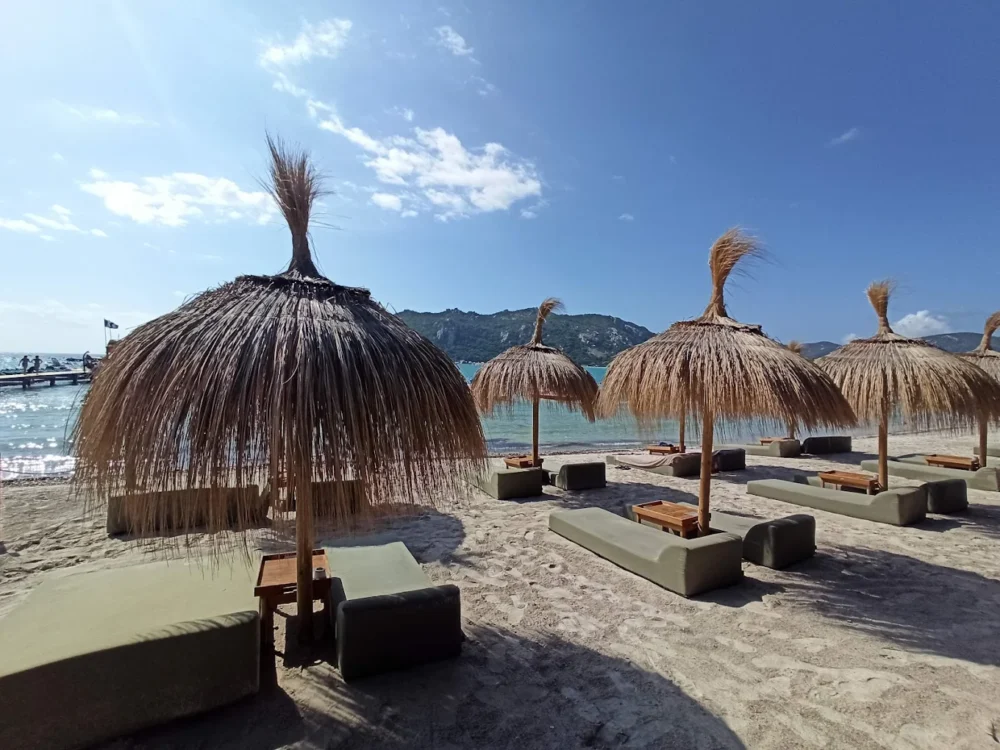Plage avec parasols en chaume et matelas.
