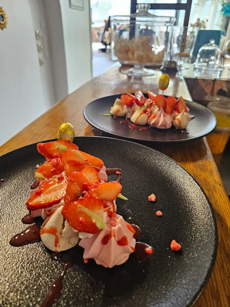 Desserts aux fraises et crème sur assiettes noires.