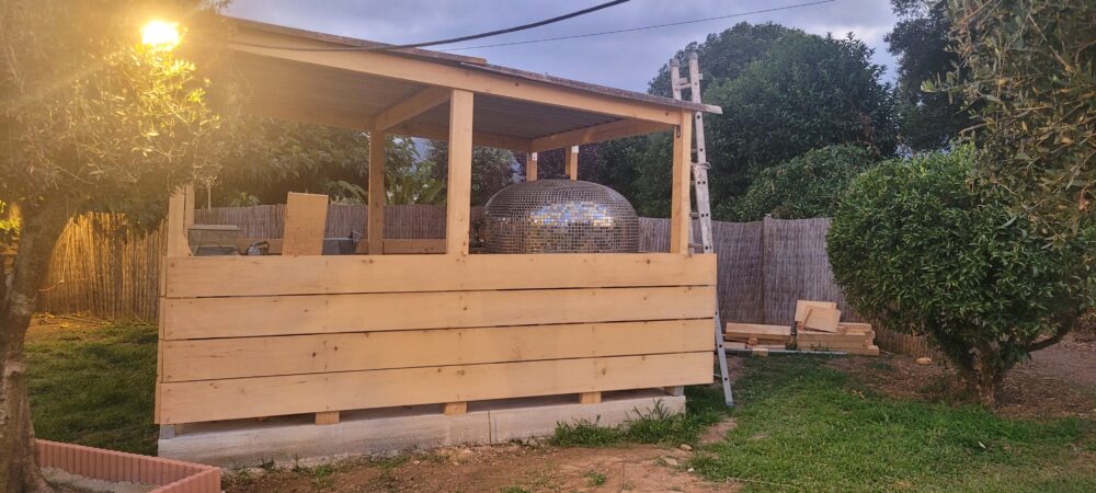 Abri en bois avec boule à facettes argentée.