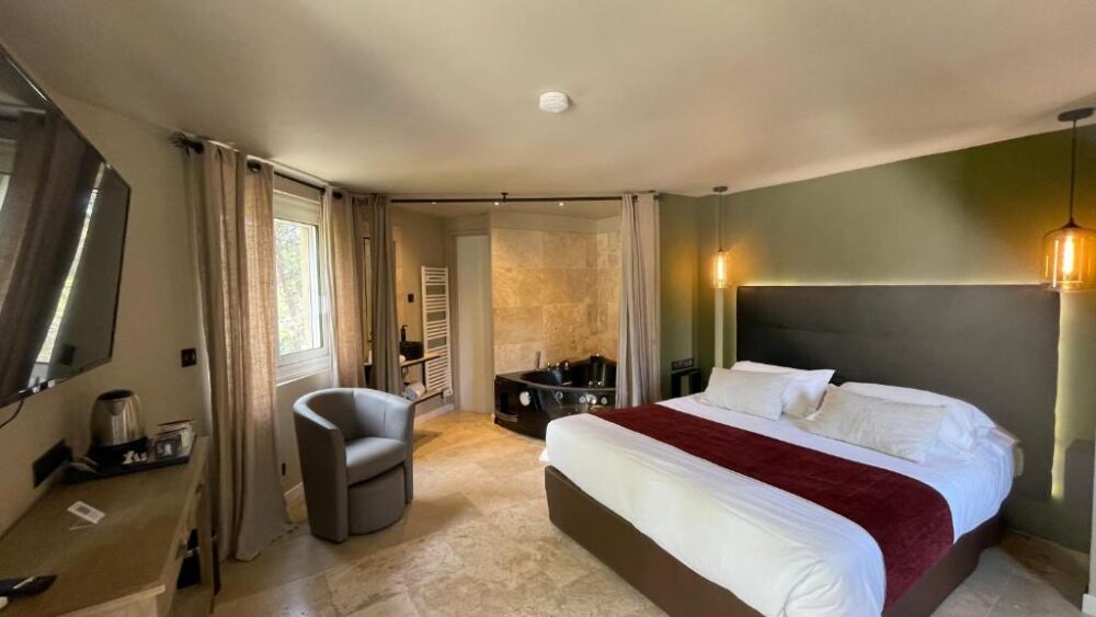 Chambre d'hôtel avec jacuzzi et grand lit.