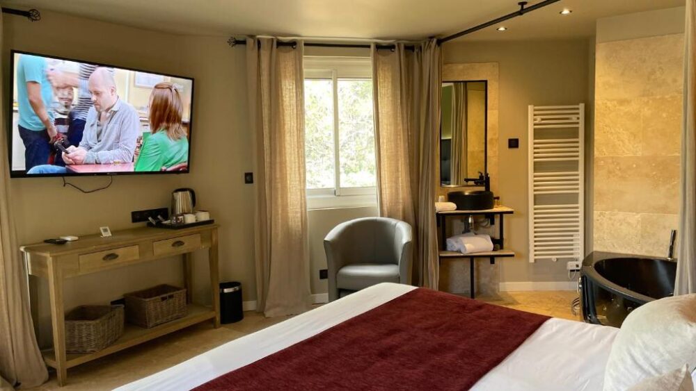 Chambre d'hôtel moderne avec baignoire noire et TV.