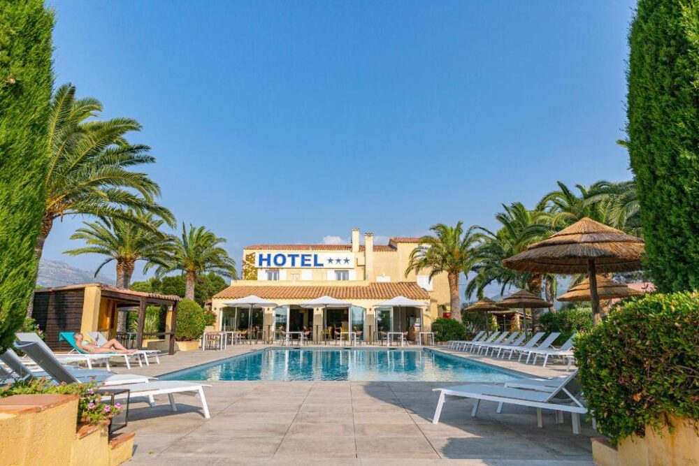 Hôtel avec piscine entourée de palmiers.