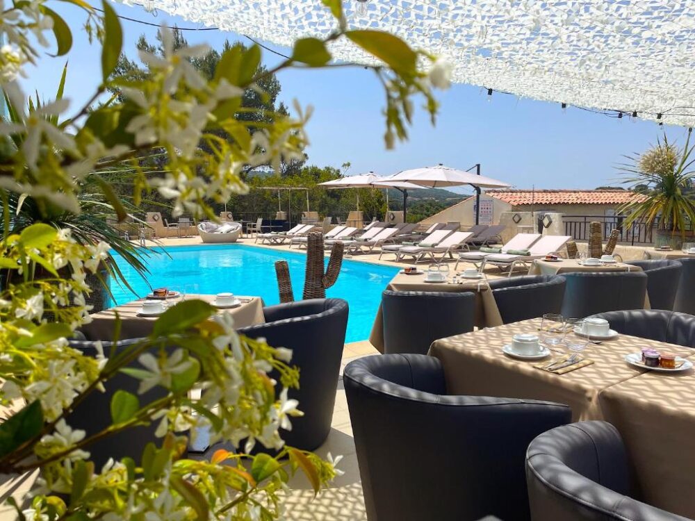 Piscine extérieure avec chaises longues et tables dressées.